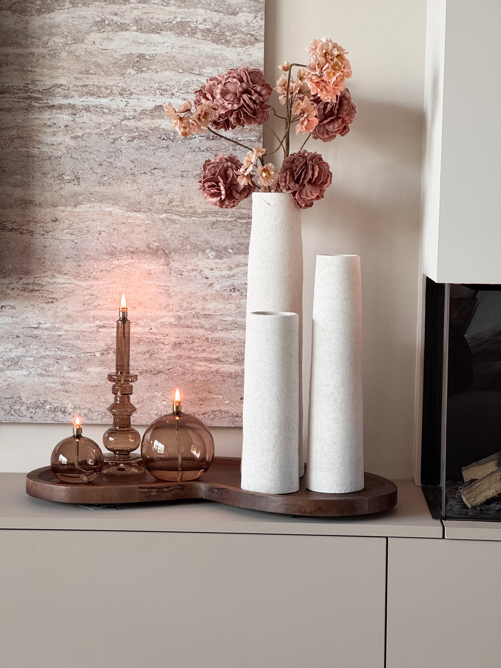 Complete woonset Walnut en Warmth met drie witte Cone vazen, een organisch houten Villeta walnut dienblad en drie brandende Peri Living olielampjes op een modern dressoir.