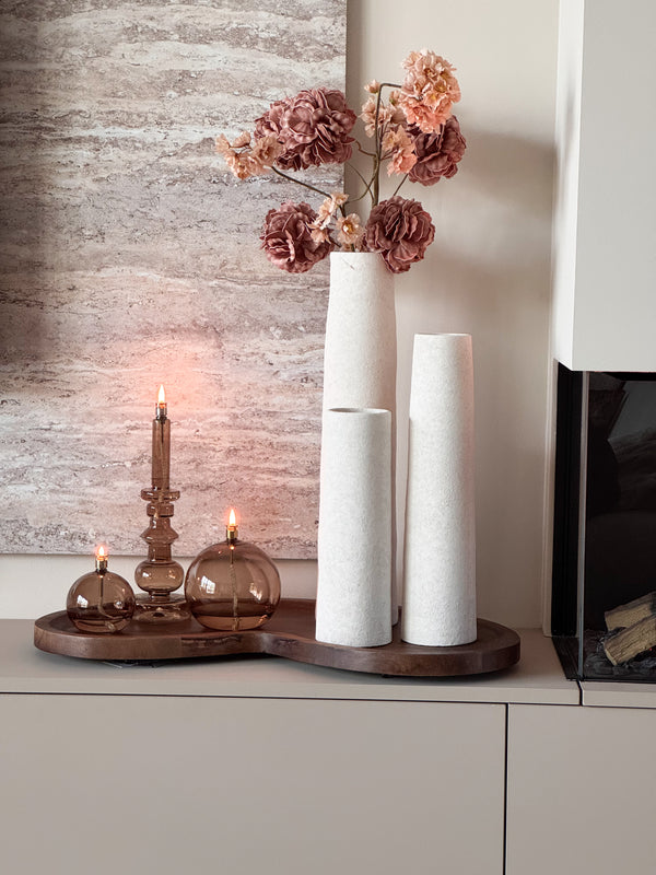 Complete woonset Walnut en Warmth met drie witte Cone vazen, een organisch houten Villeta walnut dienblad en drie brandende Peri Living olielampjes op een modern dressoir.