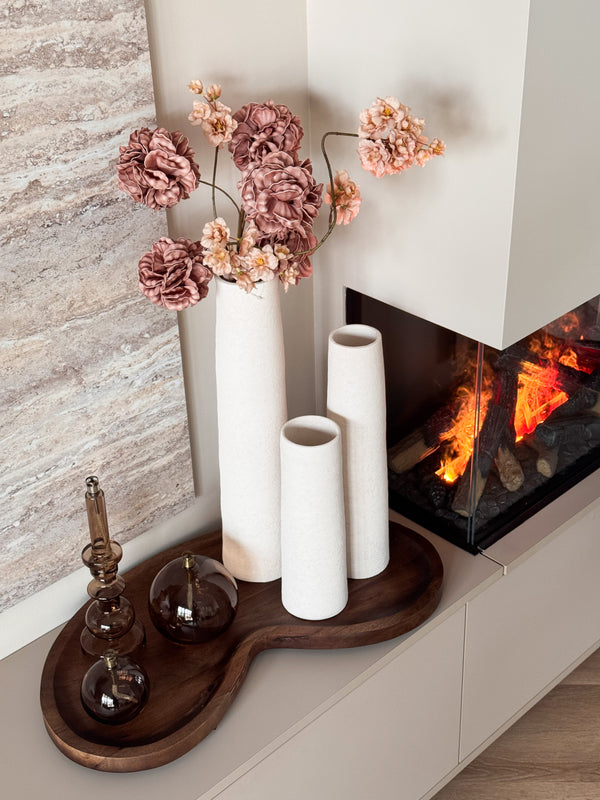 Complete woonset Walnut en Warmth met drie witte Cone vazen, een organisch houten Villeta walnut dienblad en drie brandende Peri Living olielampjes op een modern dressoir. Voordeelbundel