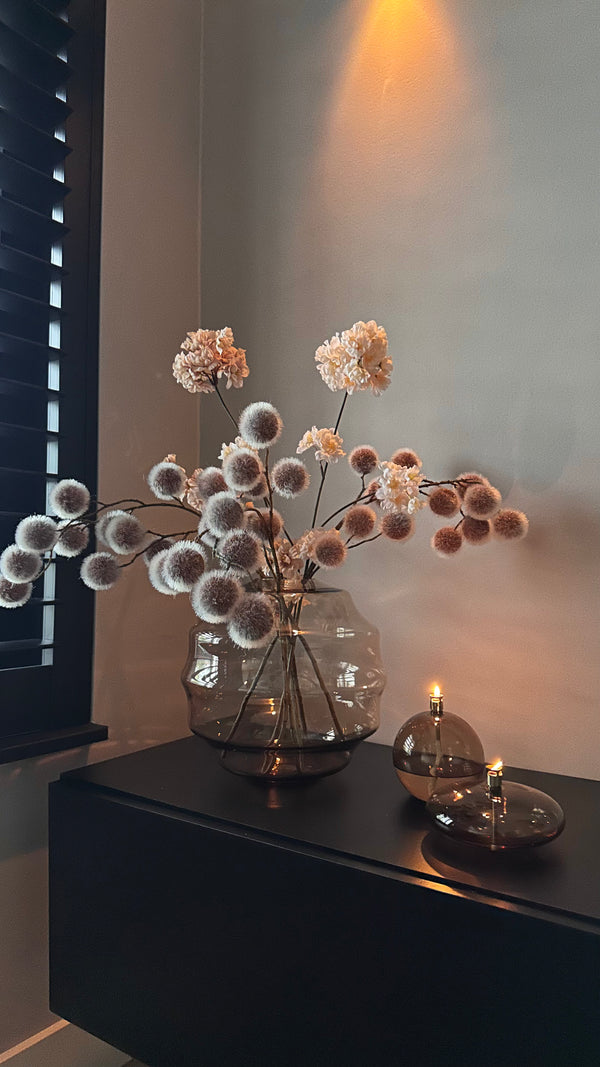 Designvaas met champagnekleurige glazen olielampjes van Peri Living op een TV meubel