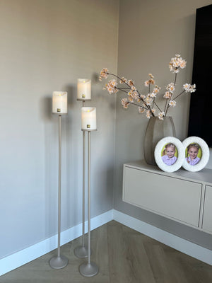 Set van 3 matbeige stalen Onah vloerkandelaren in verschillende hoogtes (100 cm, 110 cm en 120 cm) met witte PTMD LED-kaarsen.