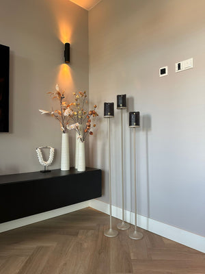 Set van 3 matbeige stalen Onah vloerkandelaren in verschillende hoogtes (100 cm, 110 cm en 120 cm) met zwarte PTMD LED-kaarsen.