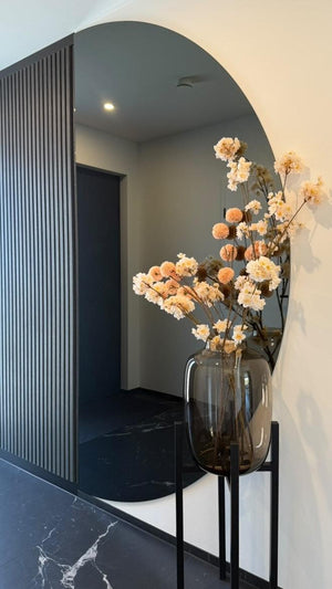 Vaas Artic L Taupe Vase the World met een prachtig boeket van kunstbloesemtakken in een hal.